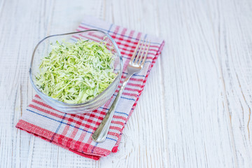 Green cabbage in a glass bowl. White background. Copy space. The concept is healthy food, diet, vegan.