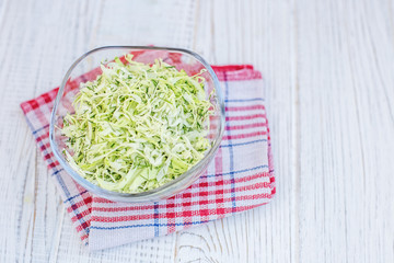 Green cabbage in a glass bowl. Salad. White background. Copy space. The concept is healthy food, diet, vegan.