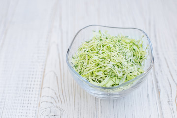 Green cabbage in a glass bowl. Salad. Wooden background.  Copy space. The concept is healthy food, diet, vegan.