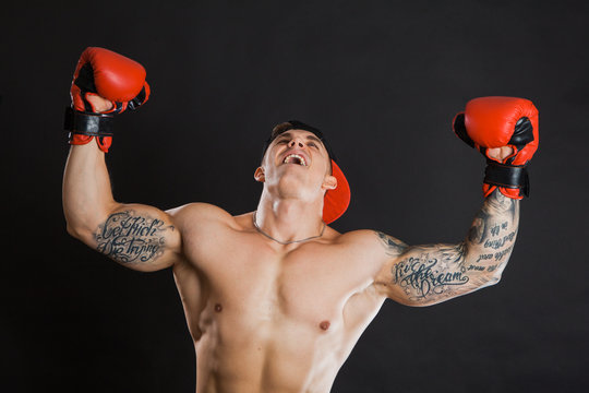 Muscular man in red boxing gloves raising hands