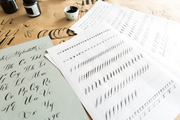 calligraphy, education, graphic design concept. lots of exercises for training skills of calligraphy with help of special supplies like black ink, brushes and white lined sheets