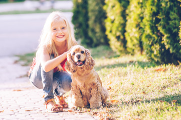 Little beautiful girl is walking with her dog in the park
