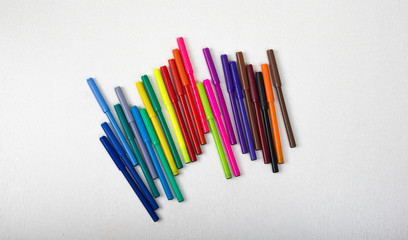 Fototapeta premium a lot of colored pencils, markers, pens, white background, row markers colored yellow, blue, red, concept, school, business, office, creativity, search ideas