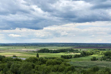 Fototapeta na wymiar View from the hill to the green valley in cloudy weather. Russia