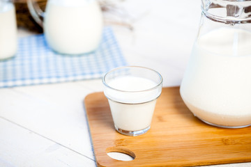 milk and glasses of milk on a wooden rustic table.