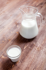 milk and glasses of milk on a wooden rustic table.