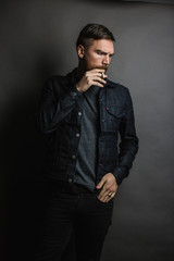 Fototapeta na wymiar man smokes cigarette in dark room with jean jacket