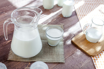 milk and glasses of milk on a wooden rustic table.