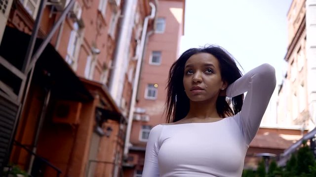 Portrait of young African American woman looking to a camera, outdoors. Portrait of a young black woman in urban background