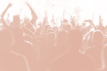 Blurred creative art background. Rear view of crowd with arms outstretched at concert. cheering crowd at rock concert. silhouettes of concert crowd in front of bright stage lights.