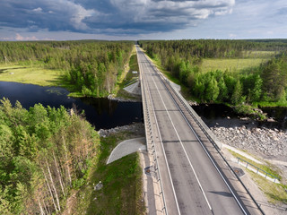 Asphalt country road across small river. Bridge over water and swamp. Karelia, Russia