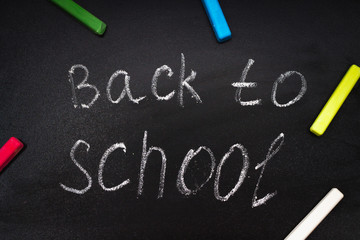 Back to school message on Blackboard inscribed with colorful chalk for background.