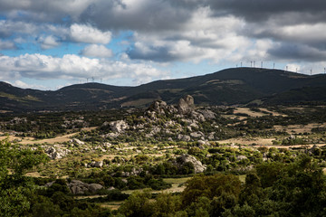 Berglandschaft mit Windr&auml;dern und Wolken am Himmel
