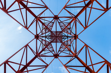 Bottom view of power pylons with blue sky on background.
