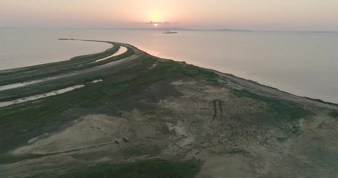 Aerial drone view of flock of birds flying away under the sea at the sunset.