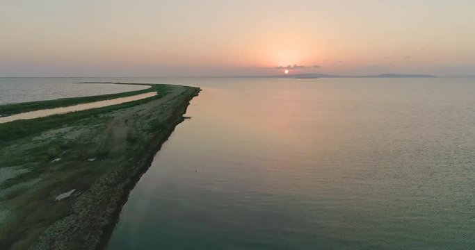 Aerial drone view of flock of birds flying away under the sea at the sunset.