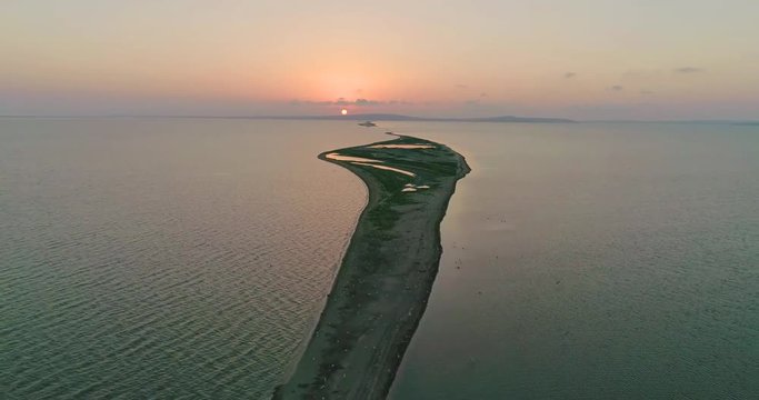 Aerial drone view of flock of birds flying away under the sea at the sunset.