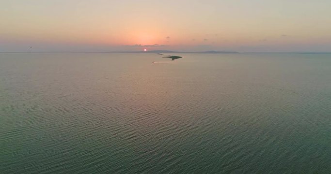 Aerial drone view of flock of birds flying away under the sea at the sunset.