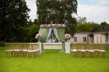 Beautiful wedding ceremony outdoors. Decorated chairs stand on the grass. rustic style.
