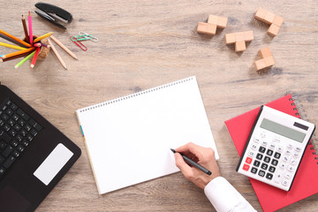 Man writing note at the blank notebook on the office desk