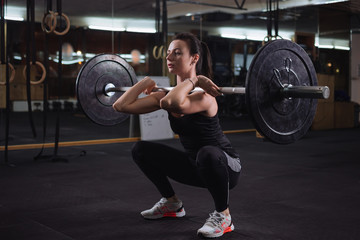 Fototapeta na wymiar Pretty young woman doing squats at the gym