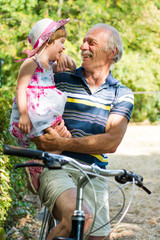 Grandpa laughing on bicycle with granddaughter