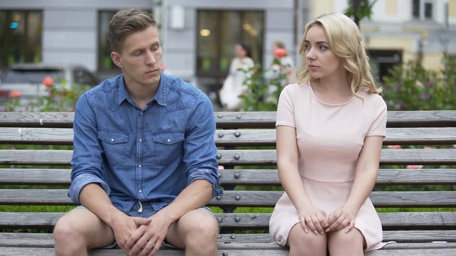 Couple sitting on bench after having fight, making up and kissing, relationship