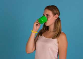 Young pretty girl drinks a cup of hot beverage, studio  
