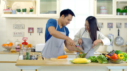 Young asian couple are teasing while cooking in the kitchen.