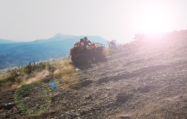 Three young guys are driving an ATV up a mountain road © fifg