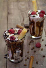 Delicious milkshake with ice cream, raspberries, chocolate, cinnamon and coffee beans on wooden background