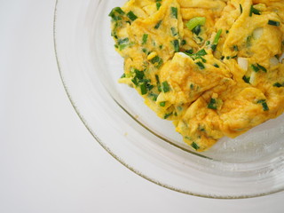 Deep fried egg omelet with chopped spring onion pieces, glass plate, white background