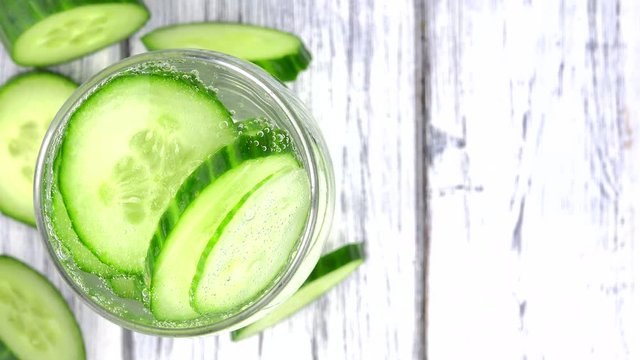 Portion of Cucumber Water rotating on a wooden plate (not loopale; 4K)