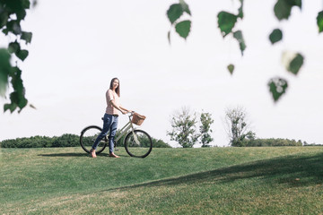 Young woman with vintage bicycle on lawn looking into distance