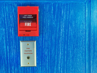 Red color fire alarm on blue color wall in a house