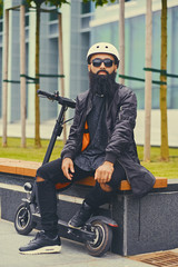 A man relaxing on a bench after riding by electric scooter.