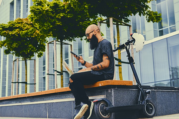 A man riding by electric scooter and using a smart phone.