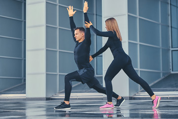 Obraz premium Fitness couple is stretching over modern building background.
