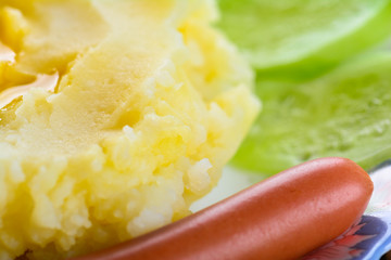 Mashed potatoes with sausages and cucumber slices