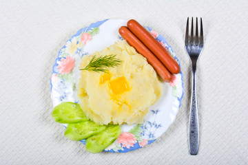 Mashed potatoes with sausages and cucumber slices