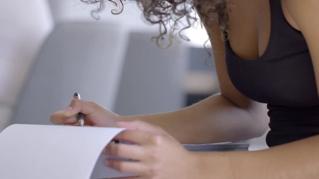 Detail of young Hispanic woman's hands filling in forms in urban modern office or downtown loft space. Hand-held slow motion 4K, shot at 60fps.