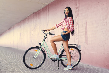 Fototapeta na wymiar A woman posing on a bicycle in a tunnel with pink walls.