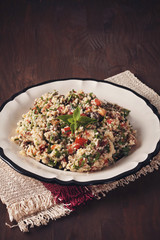 Tabbouleh - Middle Eastern vegetarian dish with couscous, tomatoes, parsley, dried raisins and mintseasoned with olive oil and lemon juice. Easy authentic recipe
