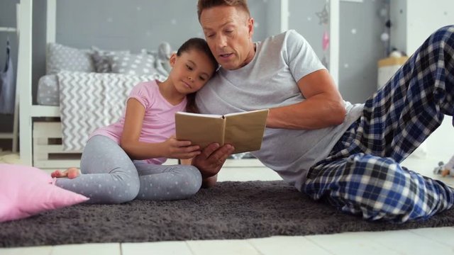 Loving father reading books with his little daugher