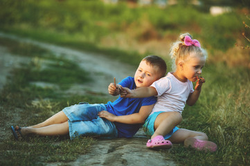 Boy and girl sitting on the road , covered in dust .