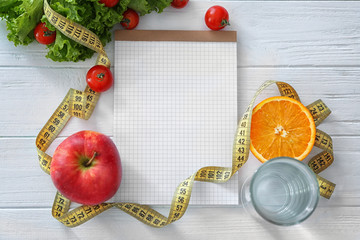 Blank notebook, healthy fresh food and measuring tape on wooden table. Weight loss concept