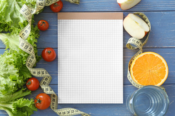 Blank notebook, healthy fresh food and measuring tape on wooden table. Weight loss concept