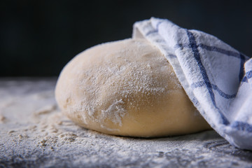 Fototapeta na wymiar Raw dough and napkin on dark table