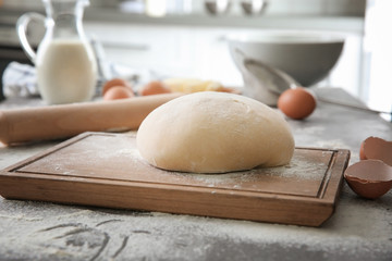 Cutting board with raw dough on kitchen table