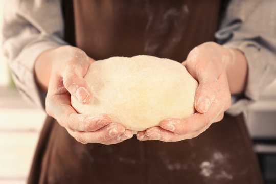 Young woman holding raw dough in hands, closeup